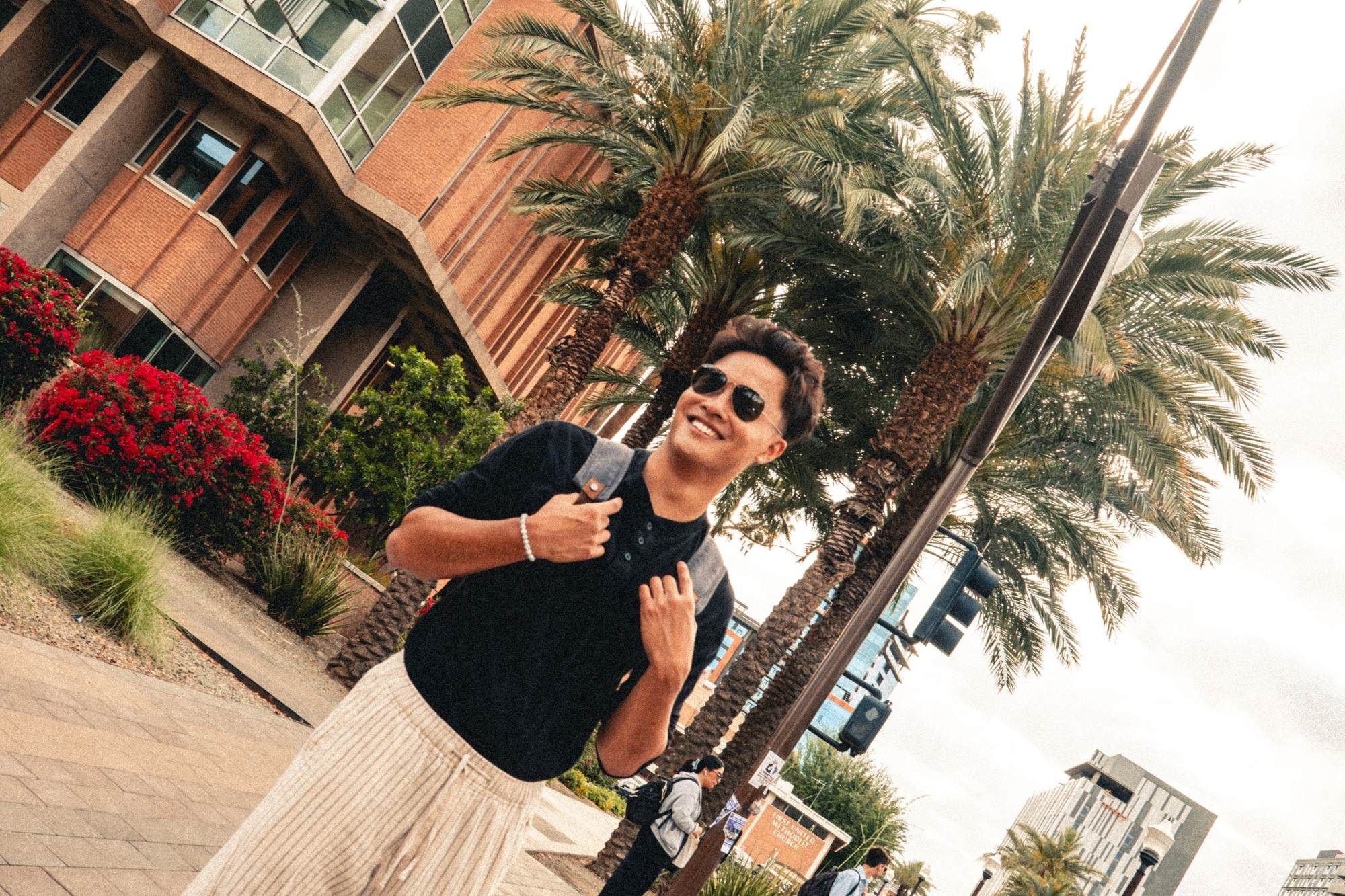 Diagonal photo of student standing in front of palm trees.