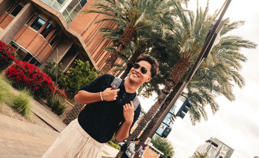 Diagonal photo of student standing in front of palm trees.