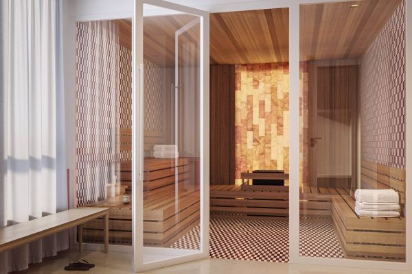 Modern sauna at VERVE Tempe featuring wood-paneled walls, built-in bench seating, and a glass door entry with soft ambient lighting.