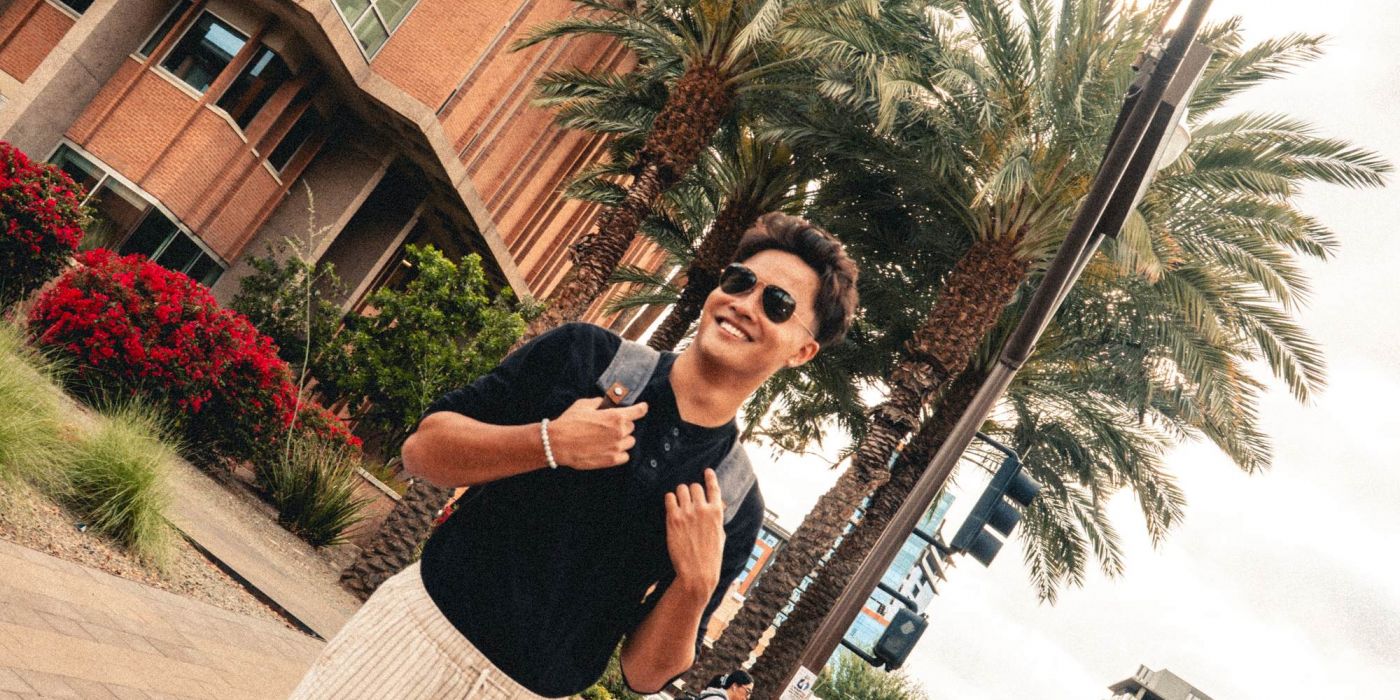 Diagonal photo of student standing in front of palm trees.