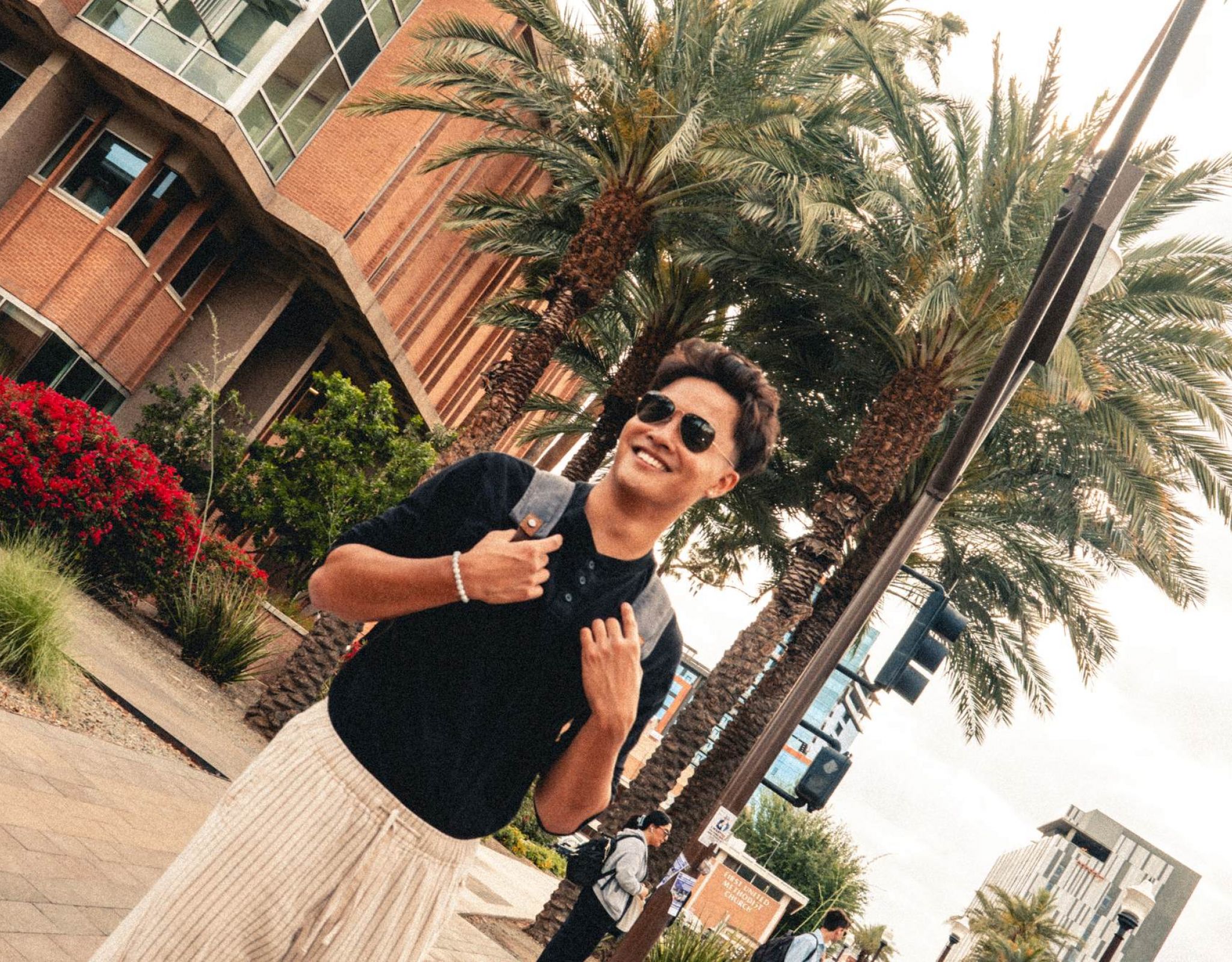 Diagonal photo of student standing in front of palm trees.