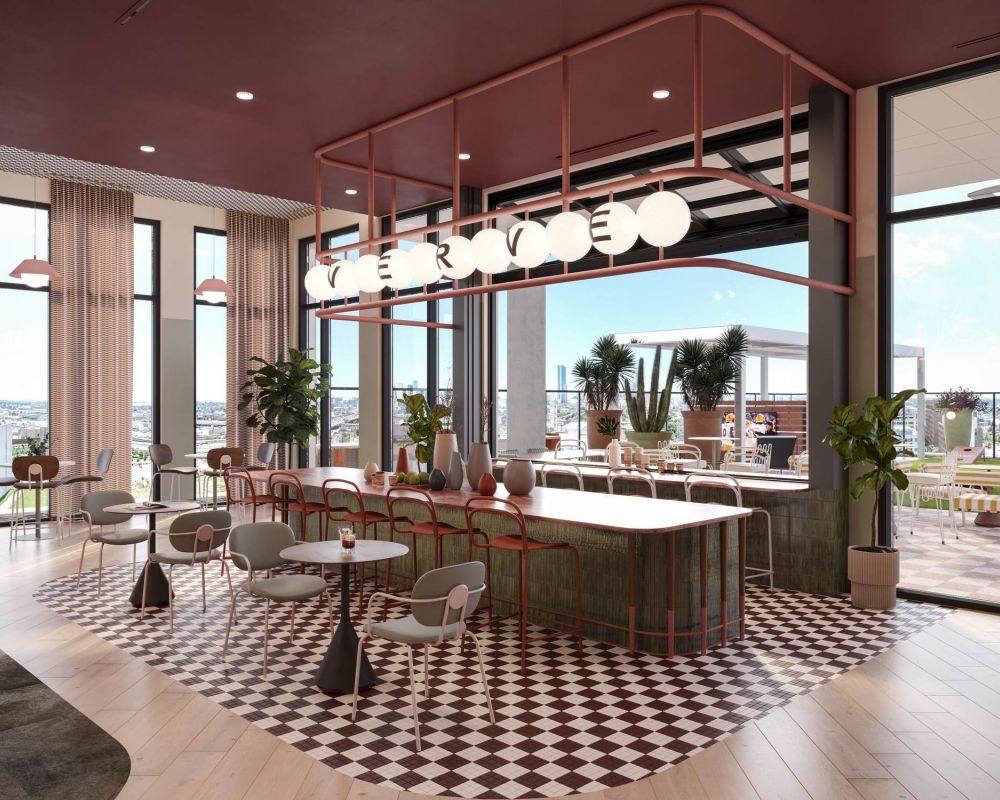 Stylish community kitchen at VERVE Tempe with a large island, globe pendant lighting, and modern seating surrounded by floor-to-ceiling windows.