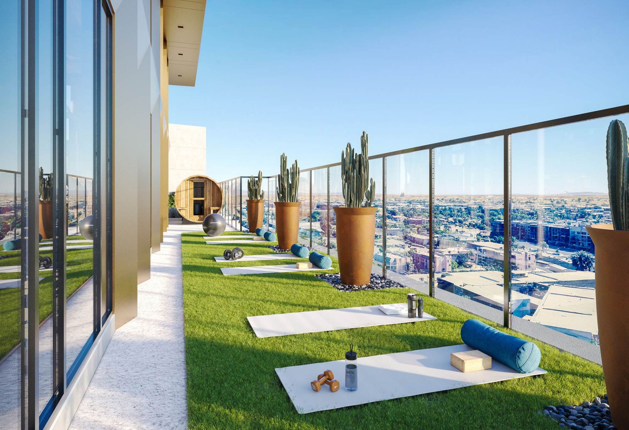Rooftop yoga area at VERVE Tempe featuring artificial grass, yoga mats, potted plants, and city views through glass railing on a sunny day.