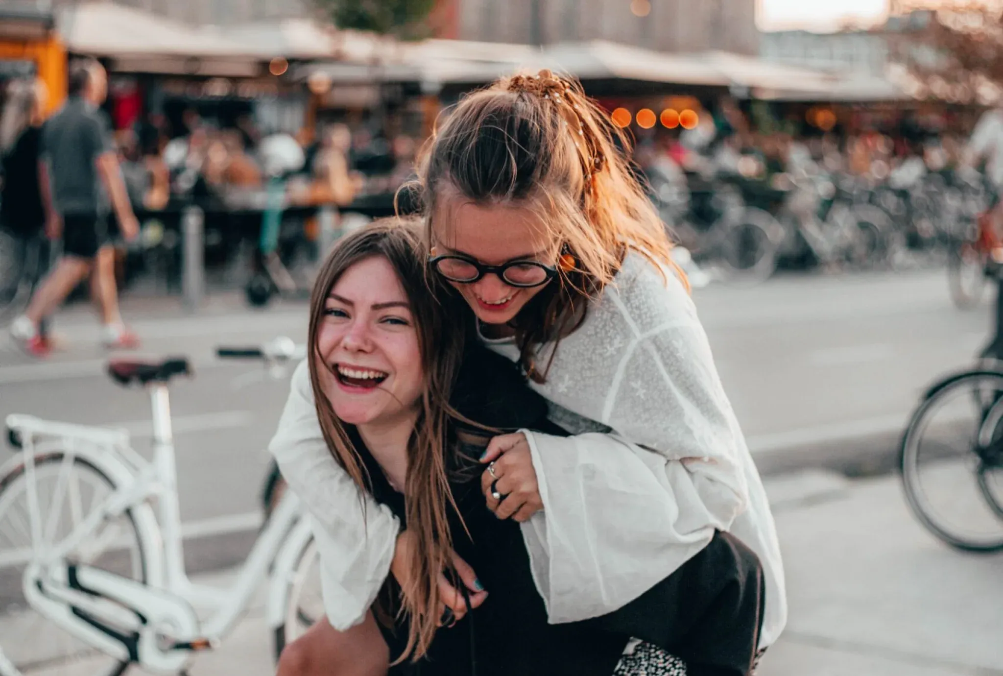 two college girls walking downtown smiling with one giving a piggy back ride to the other