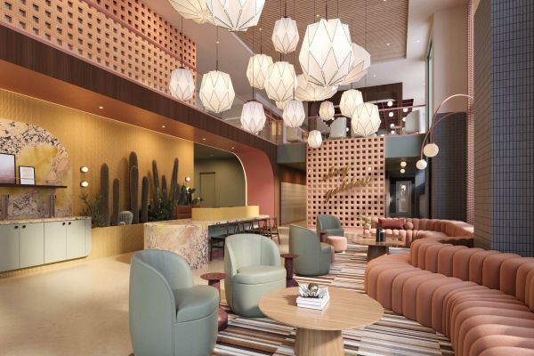 Modern lobby lounge at VERVE Tempe featuring cozy seating, layered lighting with sculptural pendant lamps, a striped rug, and a warm, welcoming coffee bar area.