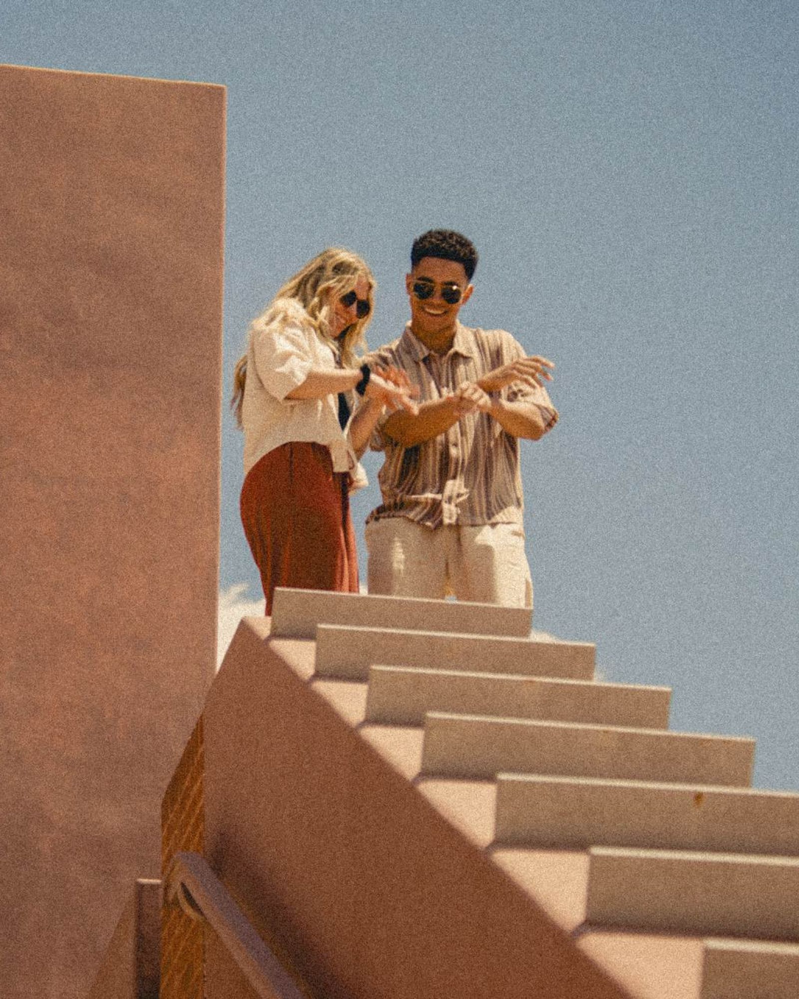 Two young residents stand at the top of modern concrete stairs at VERVE Tempe, enjoying the sunny views and stylish architecture.
