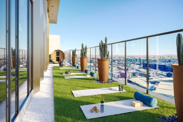 Rooftop yoga area at VERVE Tempe featuring artificial grass, yoga mats, potted plants, and city views through glass railing on a sunny day.
